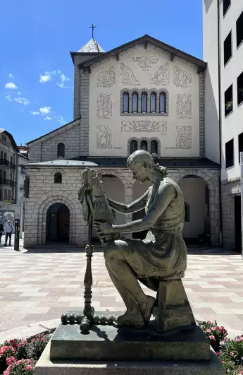 A statue in front of an old building with religious graffiti