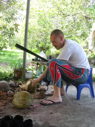 Opening coconuts with a machete. Burning dried husks works as a mosquito repellent